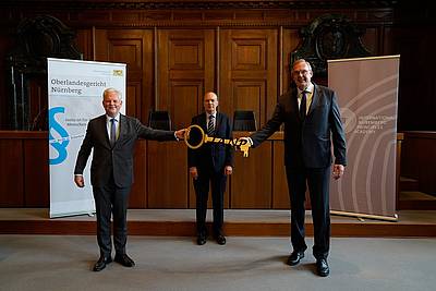 Dr. Thomas Dickert (left) hands over the symbolic key to Director Klaus Rackwitz (right) in presence of Dr. Christophe Eick (centre)