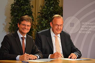 Prof. Joachim Hornegger, President of Friedrich-Alexander-Universität Erlangen-Nürnberg (left), and Klaus Rackwitz, Director of the Nuremberg Academy (right), signing the cooperation agreement